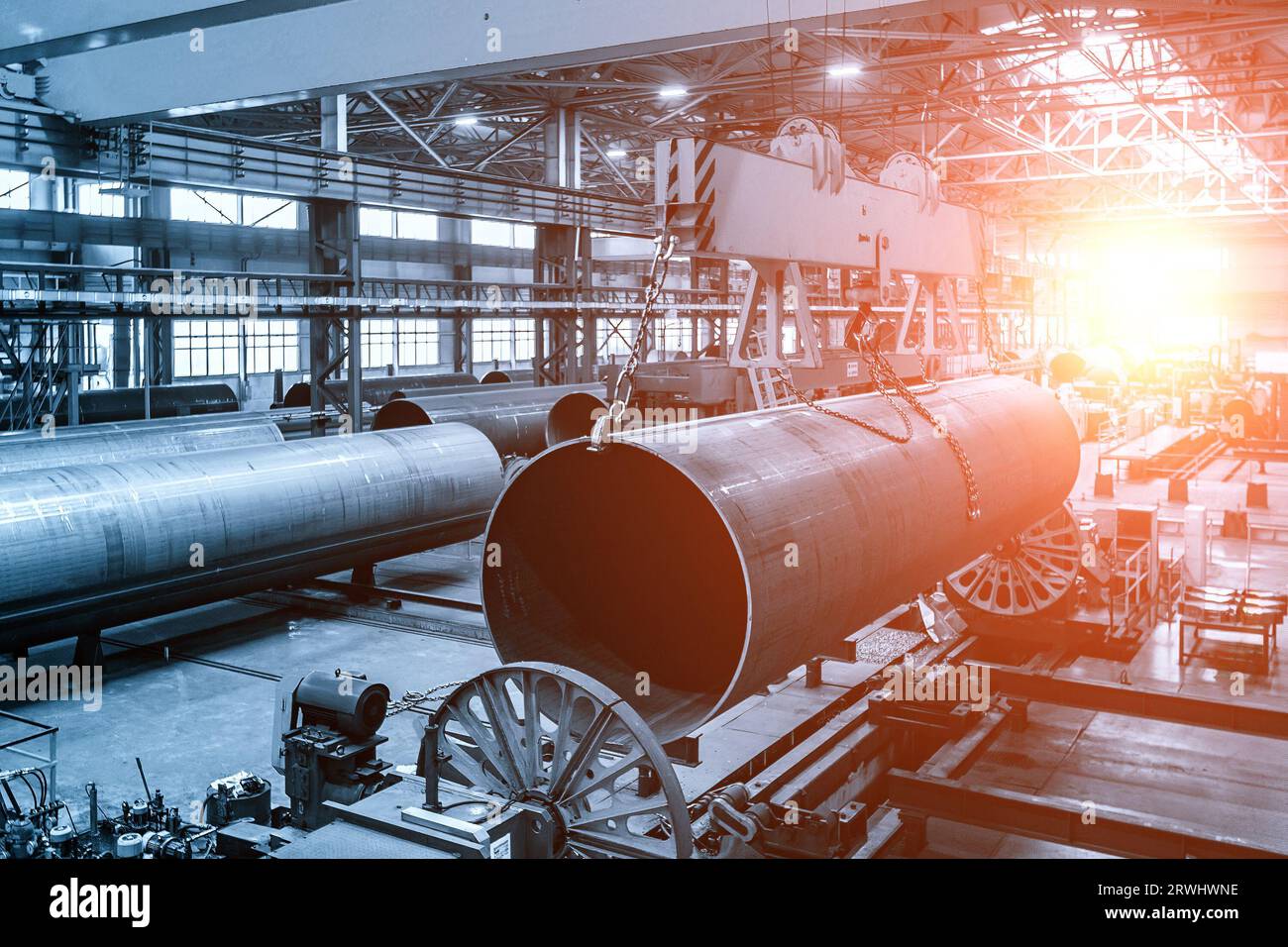 Finished pipe transportation by overhead crane in pipe factory. Stock Photo
