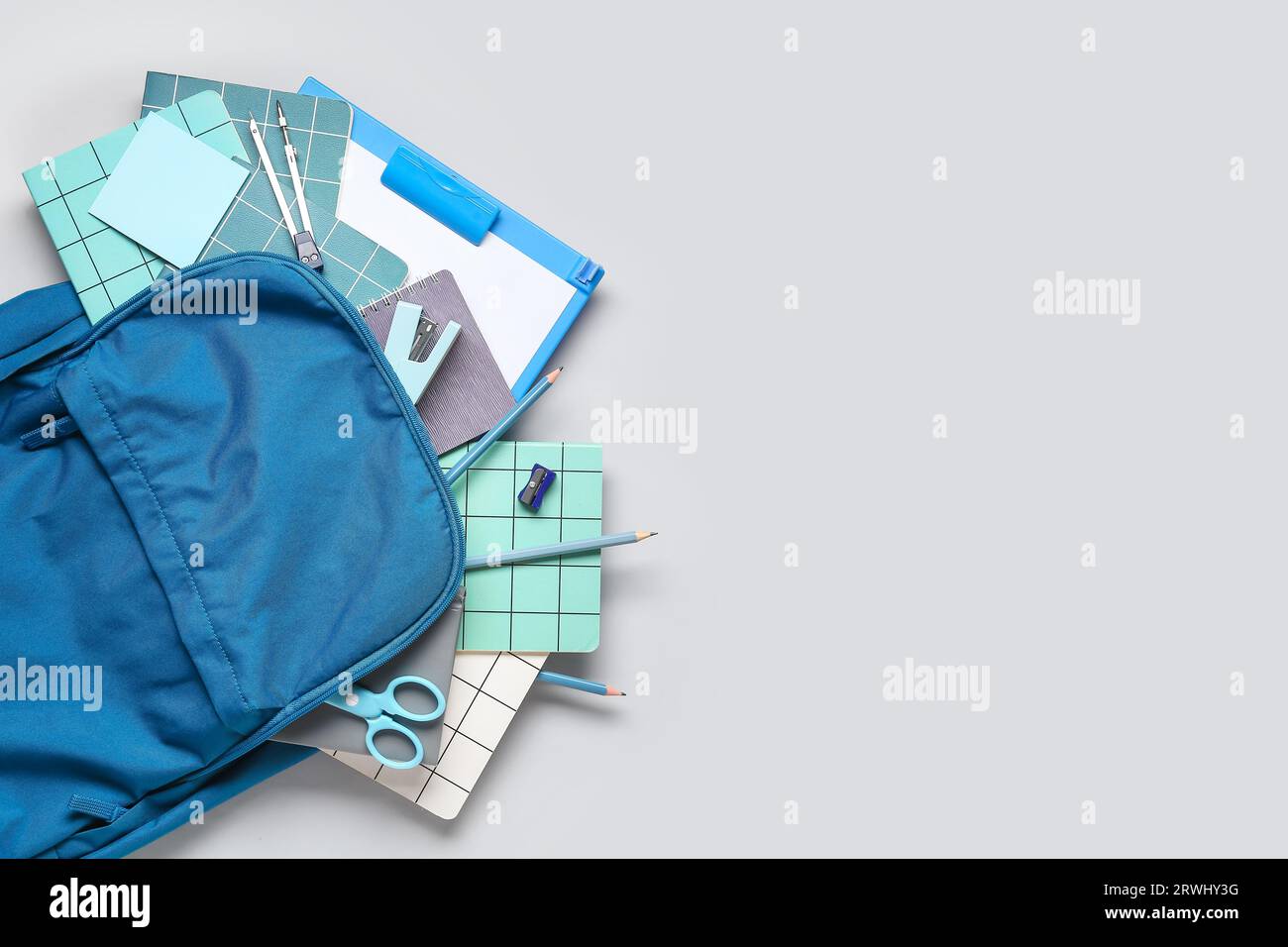 Stylish school backpack with different stationery on grey background Stock Photo