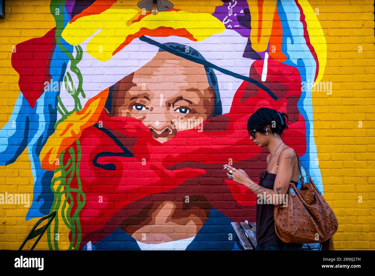 a-young-woman-walks-past-some-colourful-street-art-shoreditch-london