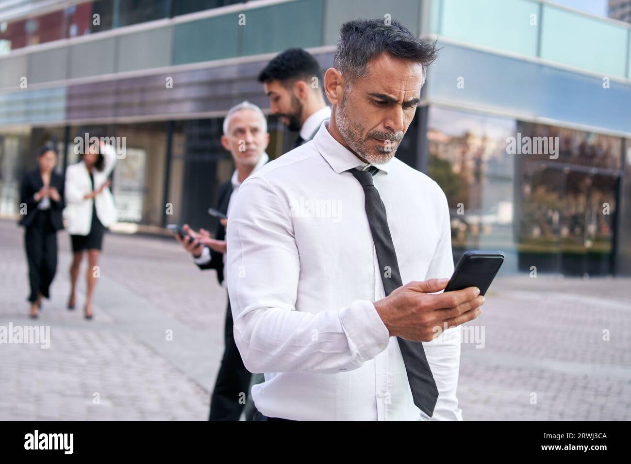 Middle-aged business man looks at cell phone concentrating walking down ...