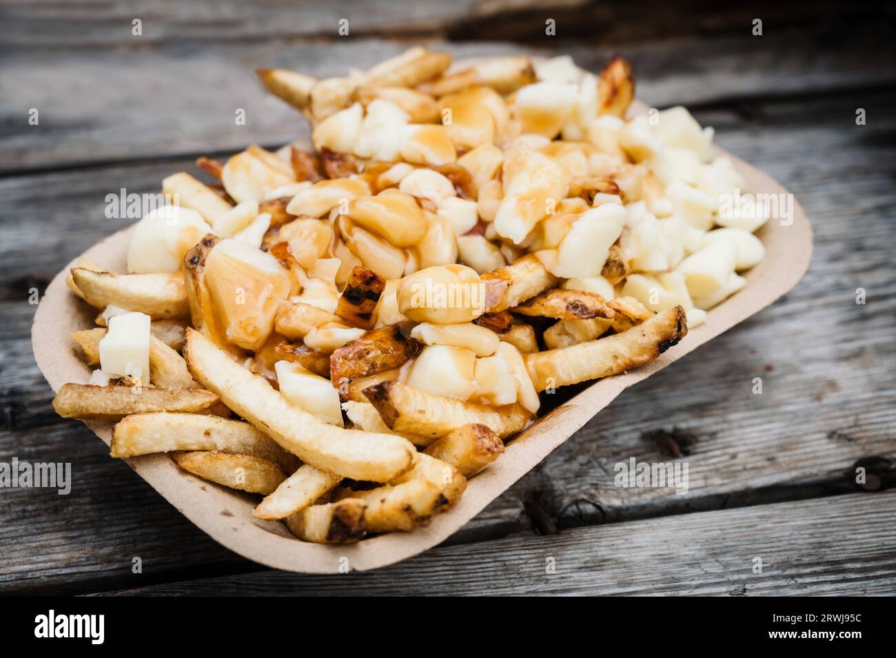 An order of poutine, a French Canadian dish of French fries, gravy, and cheese curds, at a stake street food stand. Stock Photo