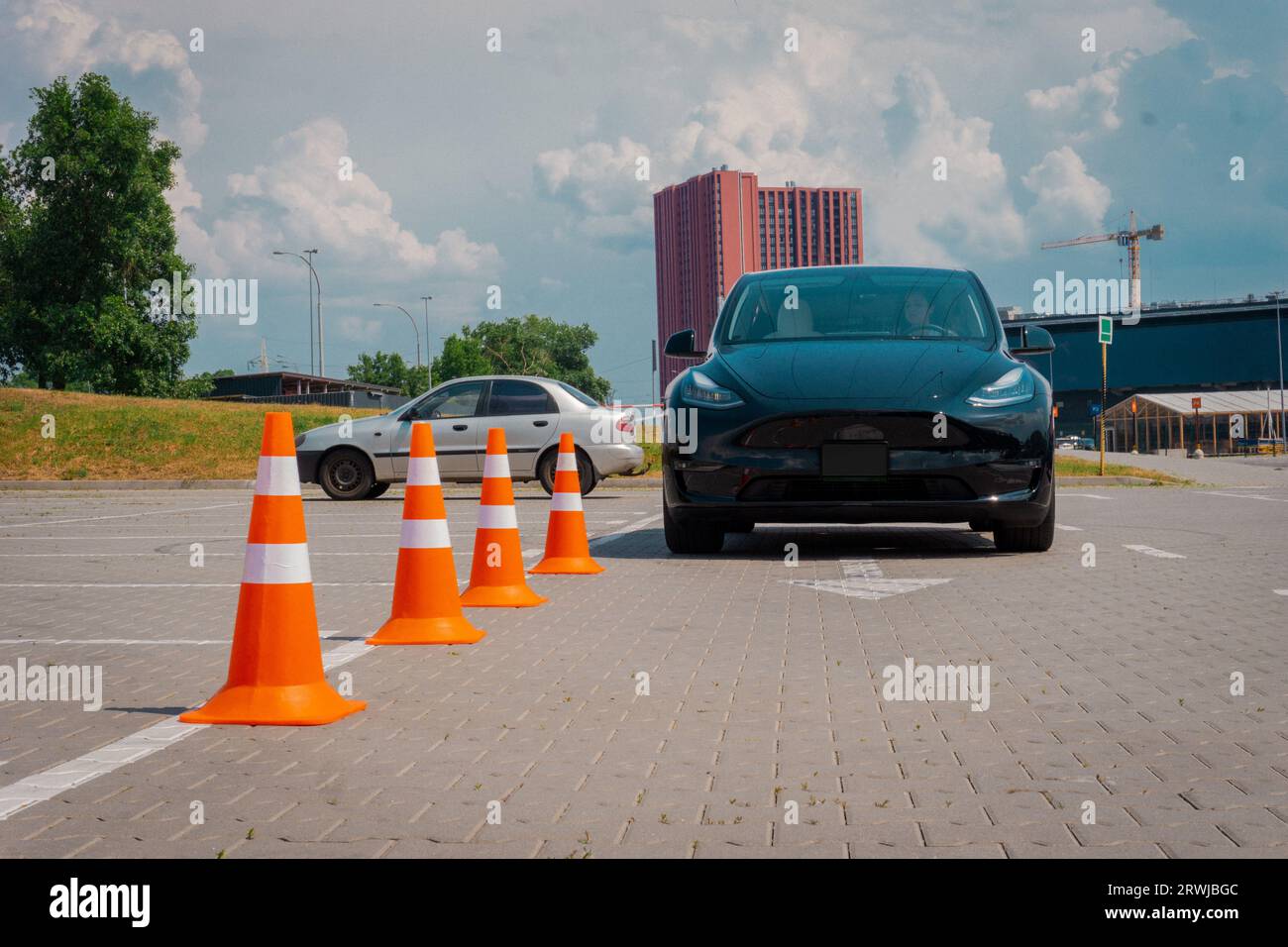 Modern car and safety cones in driving school outdoors. Young female