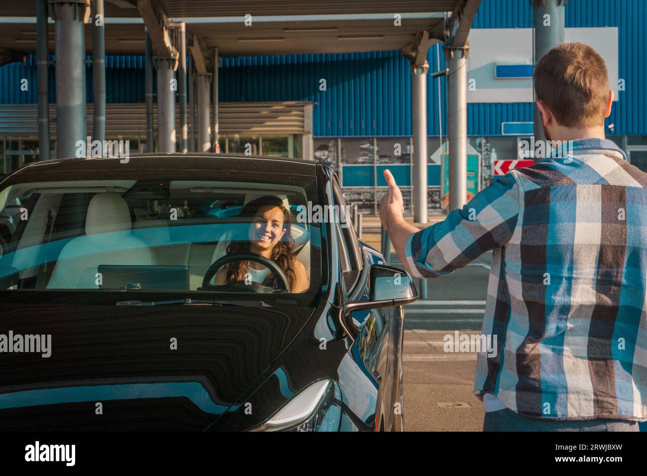 Male instructor showing thumbs up. Lady sitting inside car while ...