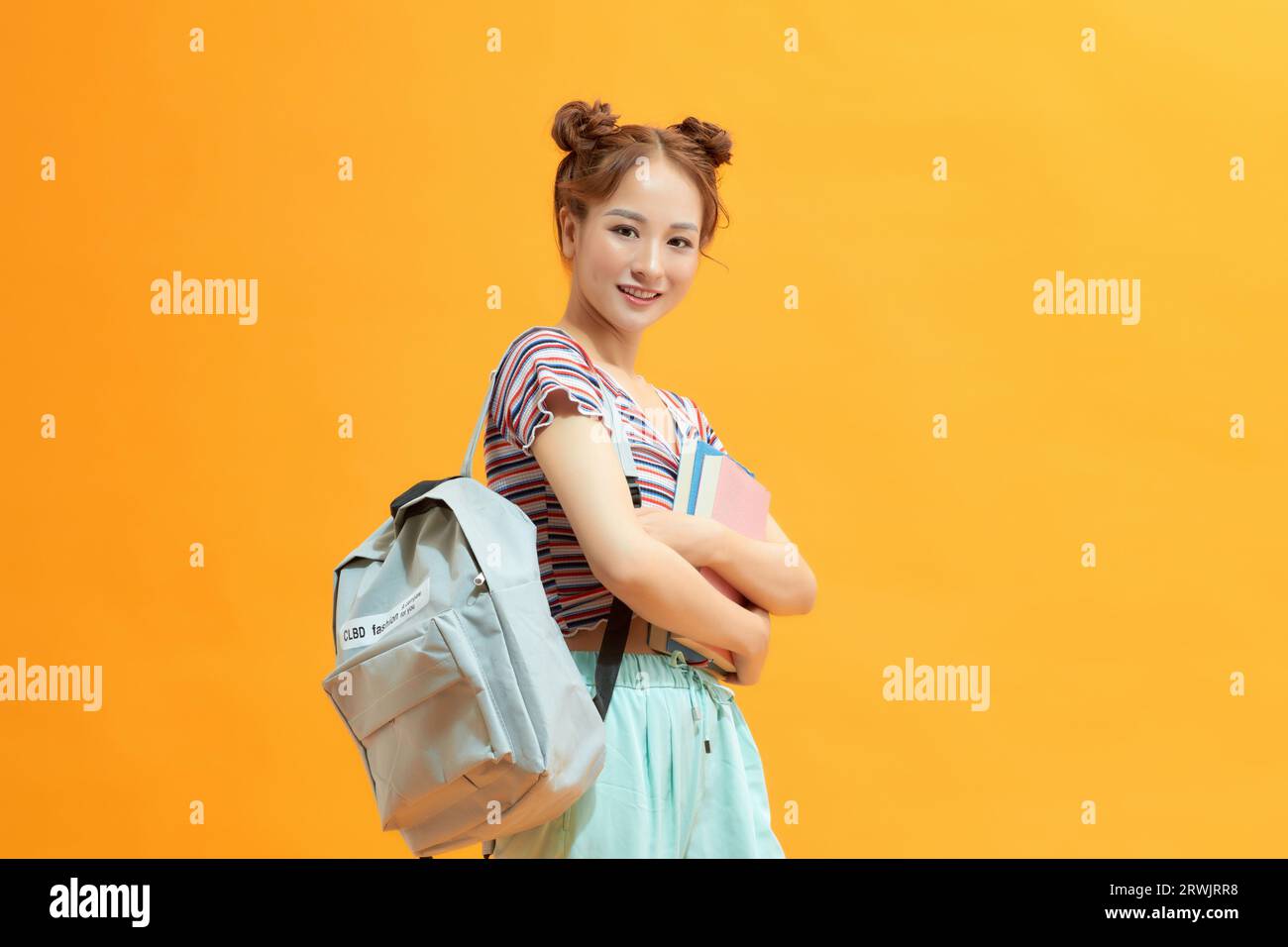 Young student holding backpack and books in studio photo Stock Photo