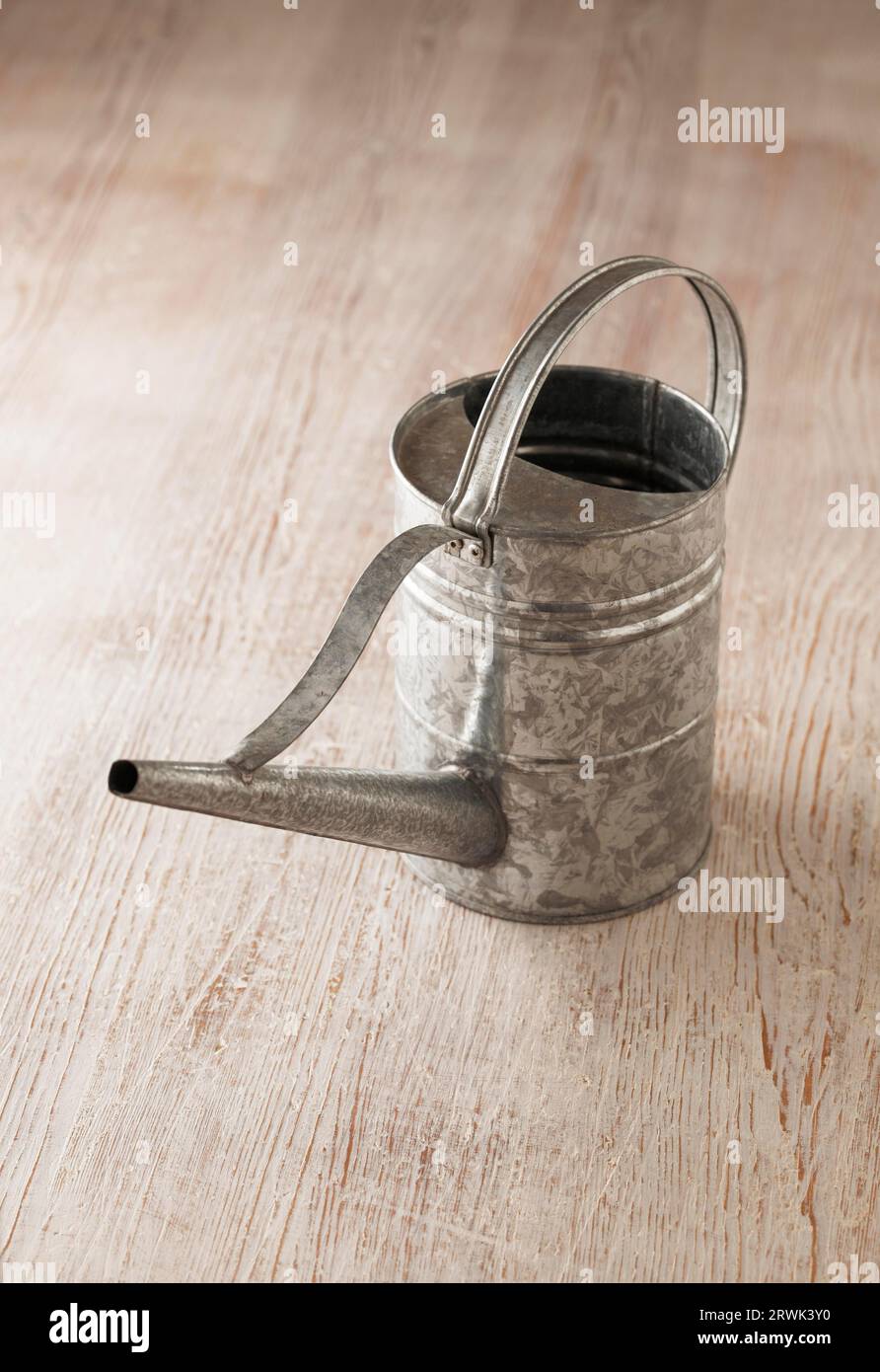 Metallic tin watering can on wooden surface Stock Photo