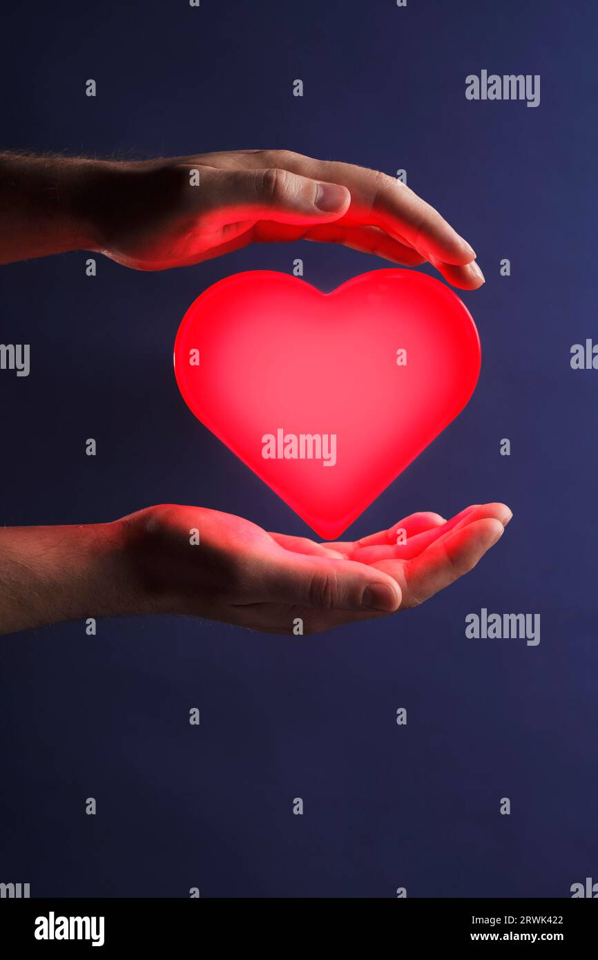 Man holding a glowing red heart in his hands Stock Photo - Alamy