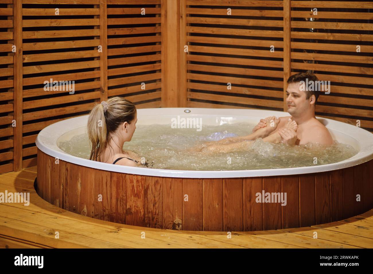 Playful woman put her feet on chest of her husband while relaxing in a