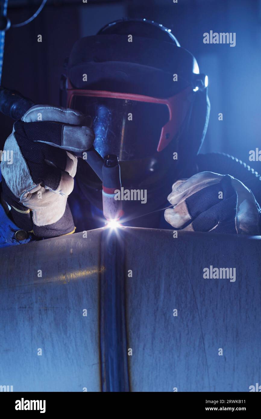 Industrial welder at work welding a stainless steel pipe Stock Photo
