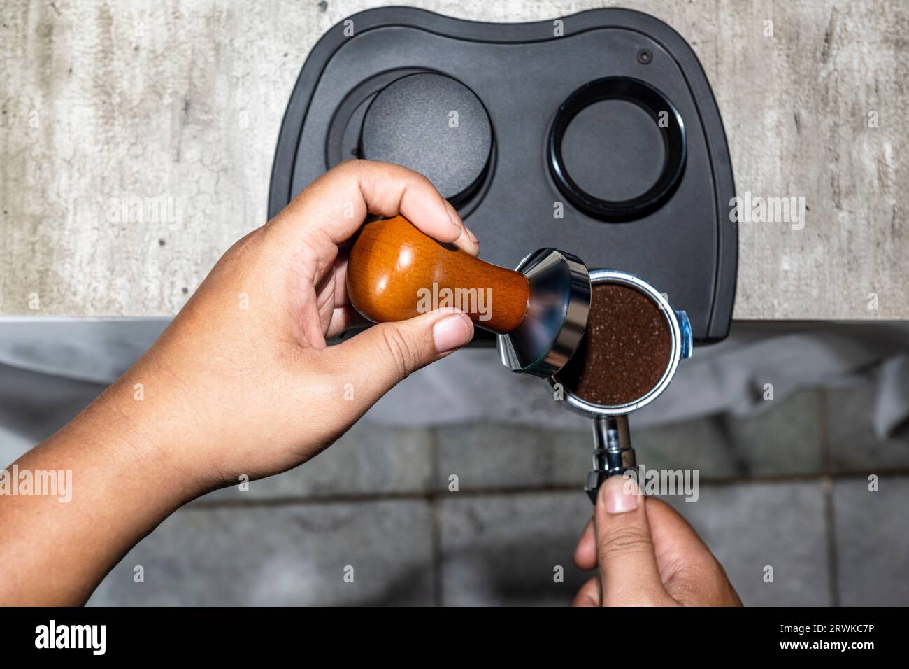 Premium Photo  Closeup of hand barista or coffee maker holding portafilter  and coffee tamper making an espresso