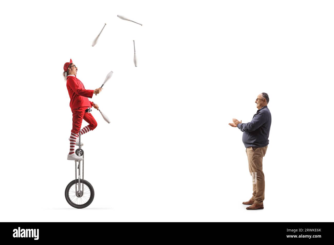 Mature man giving applause to an acrobat riding a giraffe unicycle and juggling isolated on white background Stock Photo