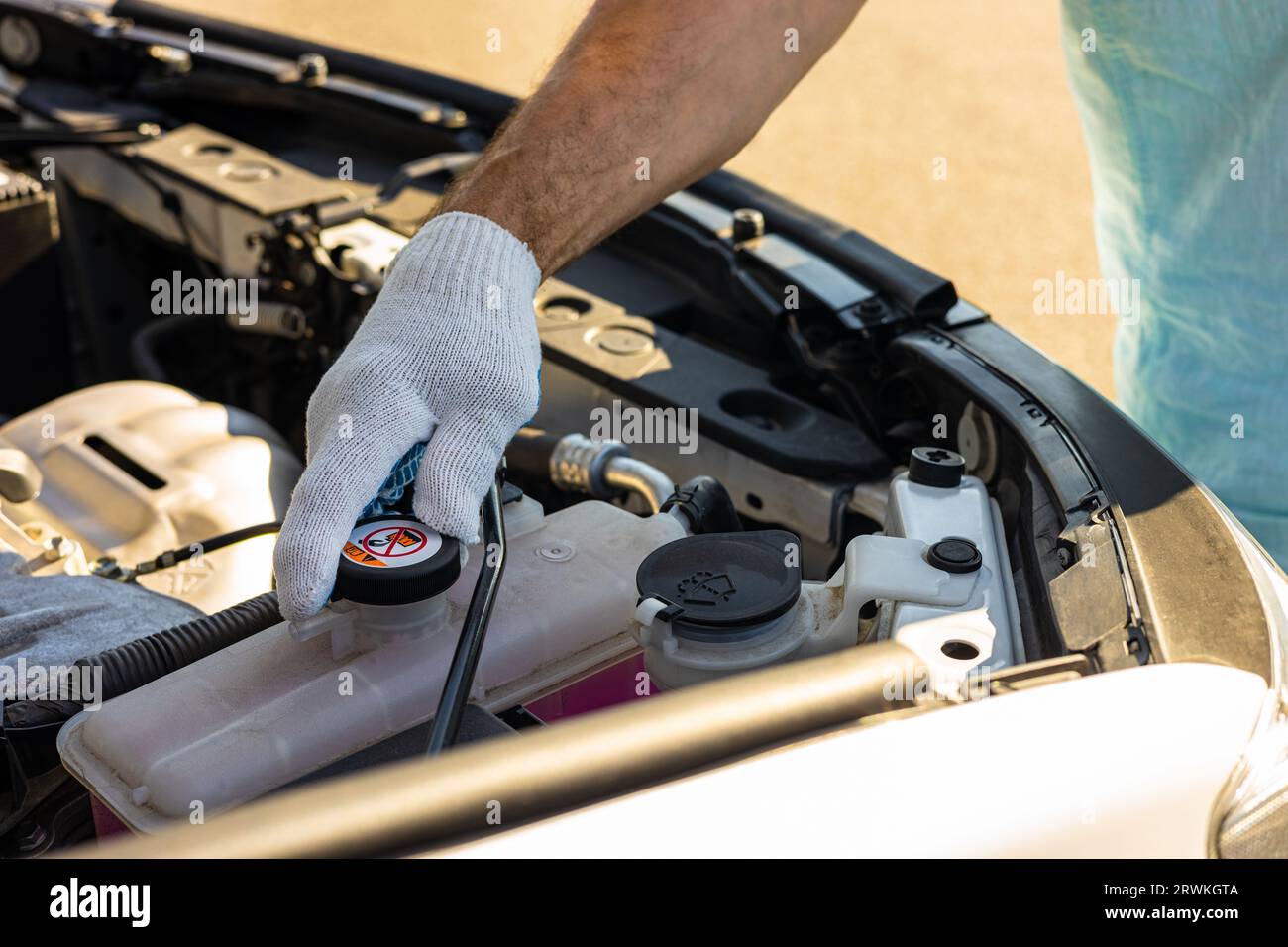 driver check the coolant level in the engine compartment of the car