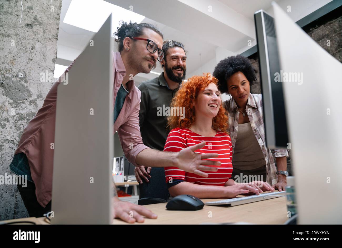 Diverse group of professionals meeting in office. IT programmers use computer, talk strategy Stock Photo