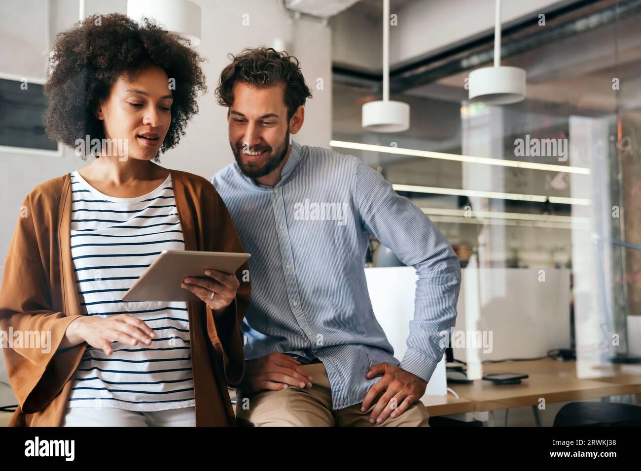 Smiling group of diverse businesspeople going over paperwork together, working in corporate office Stock Photo