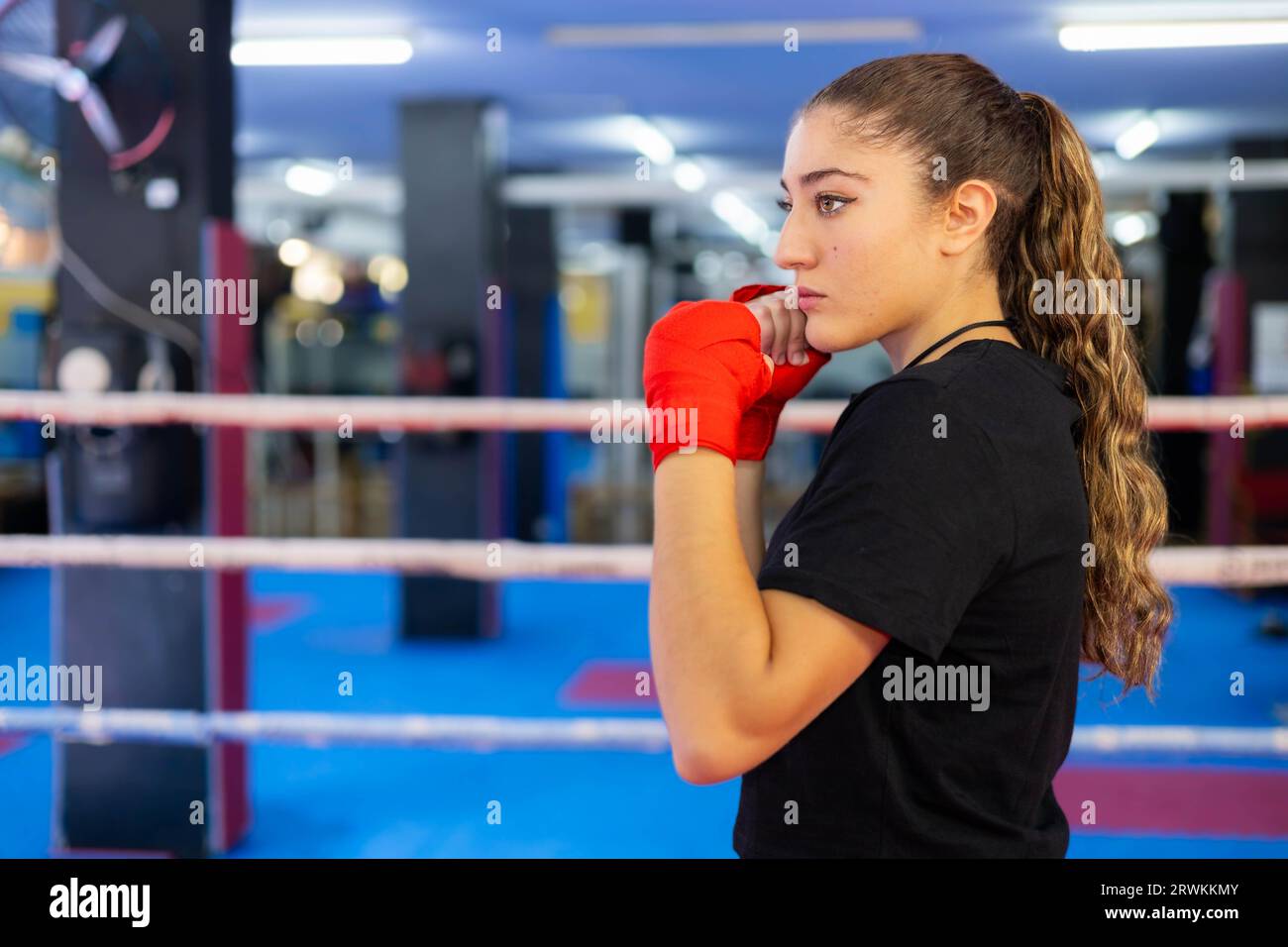 Female boxer portrait in guard position in a boxing ring. Fighting