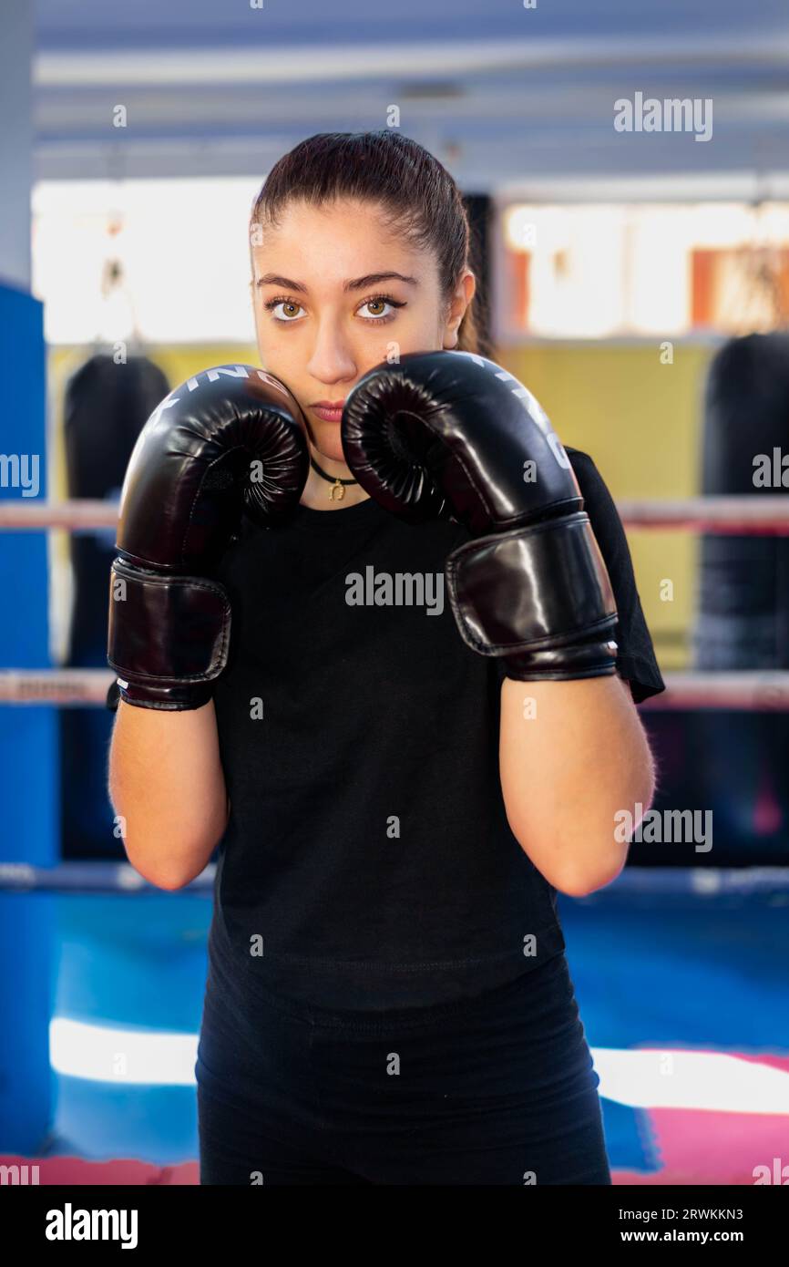 Female boxer portrait in guard position in a boxing ring. Fighting