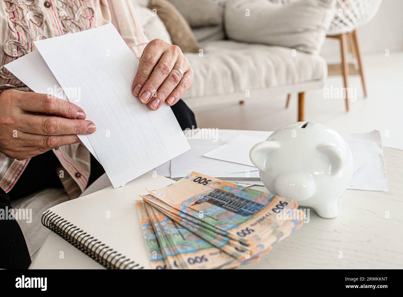 Anxious Ukrainian senior with power bills. Rising utility costs. Financial stress Stock Photo