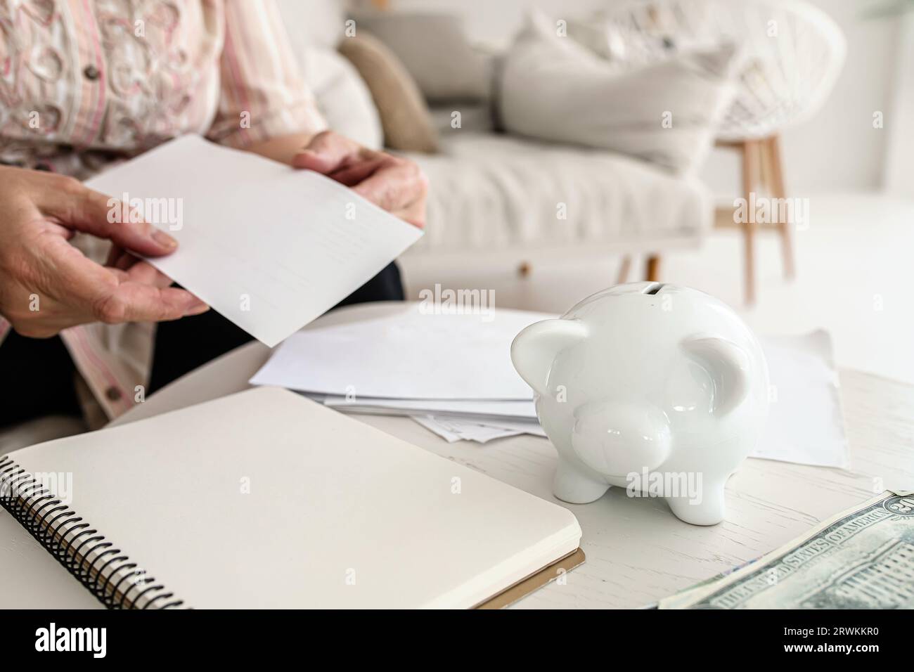 Worried elderly woman handling electricity invoices. Coping with utility bills Stock Photo