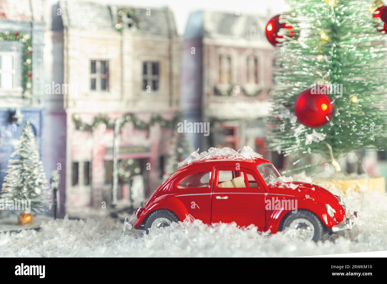 Red retro toy car. Winter snowy European street decorated for Christmas. Homemade decorated toy houses. Selective focus. St. Petersburg, Russia - Nove Stock Photo