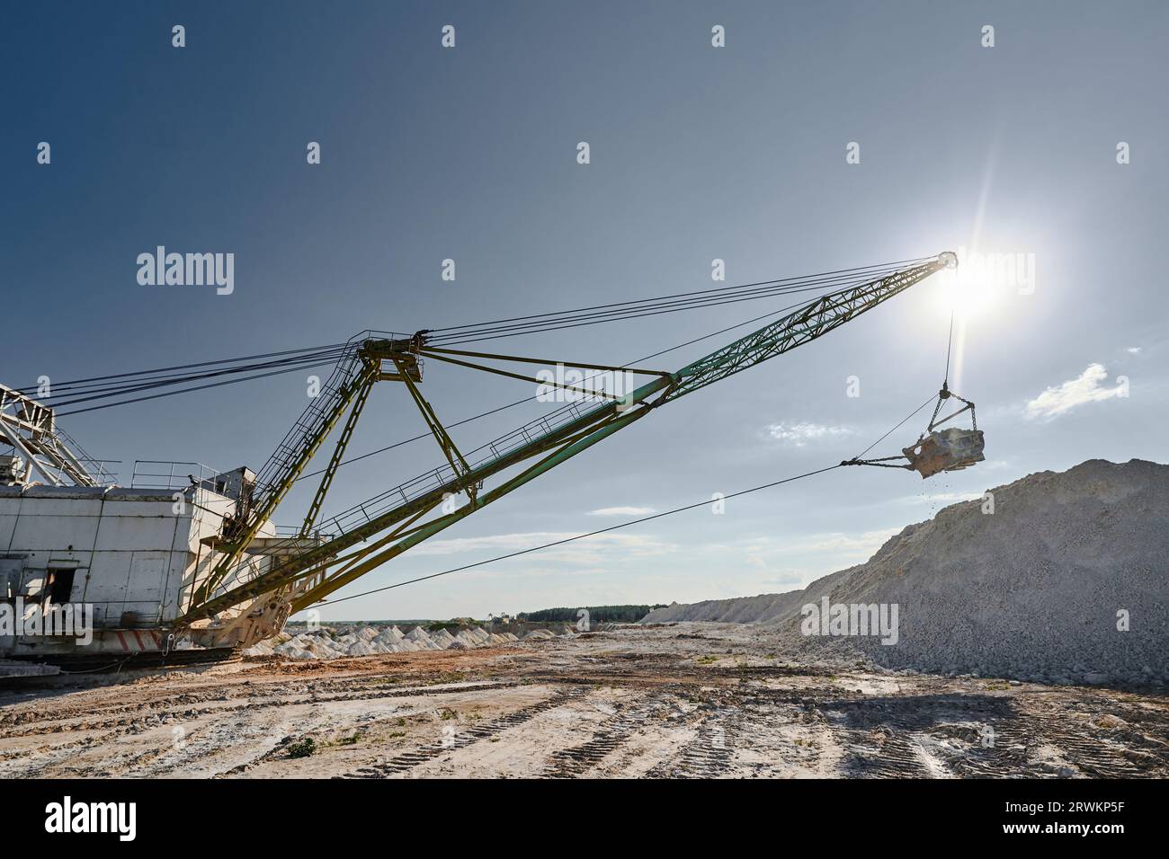 Walking excavator with bucket operates in chalk quarry Stock Photo