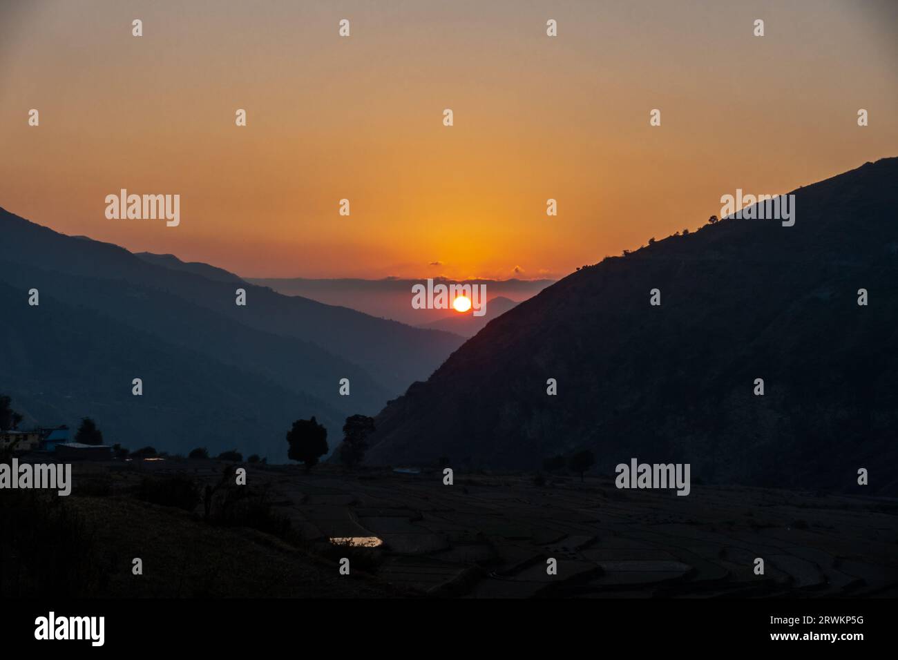 Gorgeous golden hour sunset in Uttarakhand's Himalayan Nag Tibba, featuring a round sun at its center Stock Photo