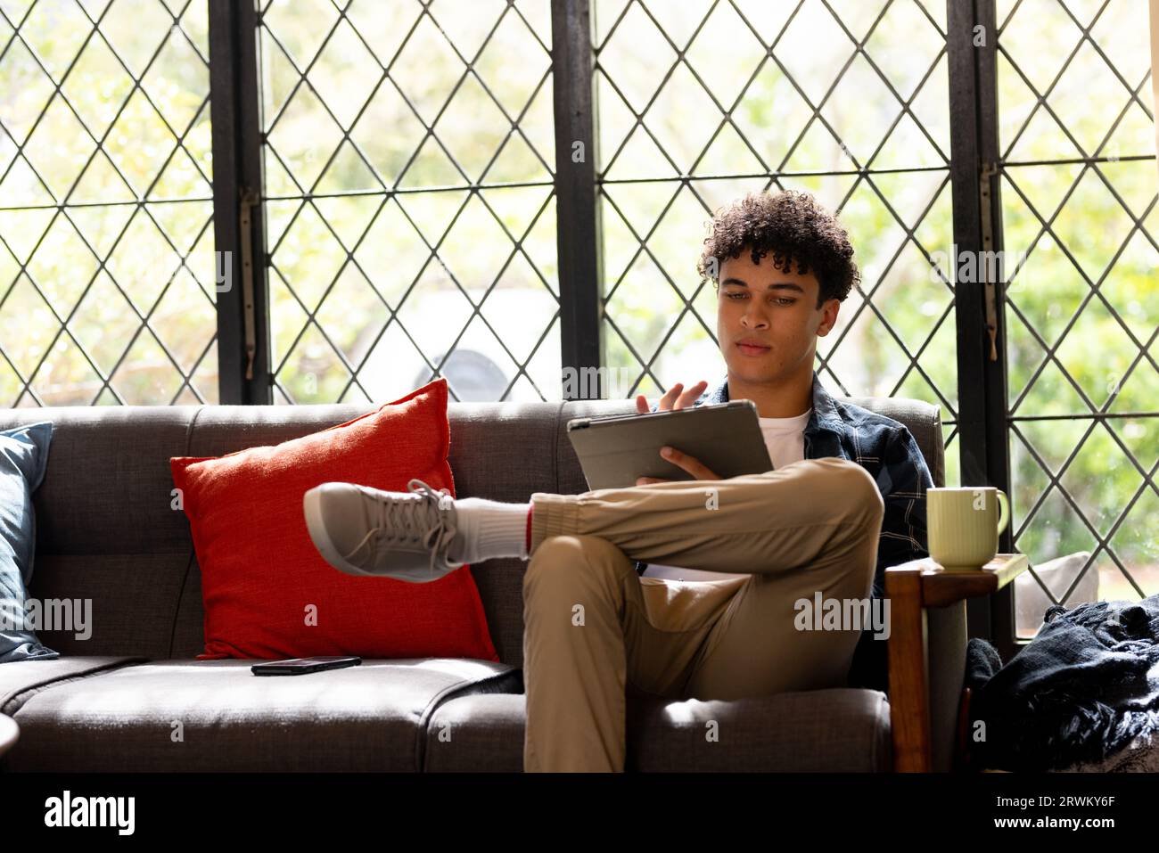 Happy biracial man working at home, and using tablet Stock Photo