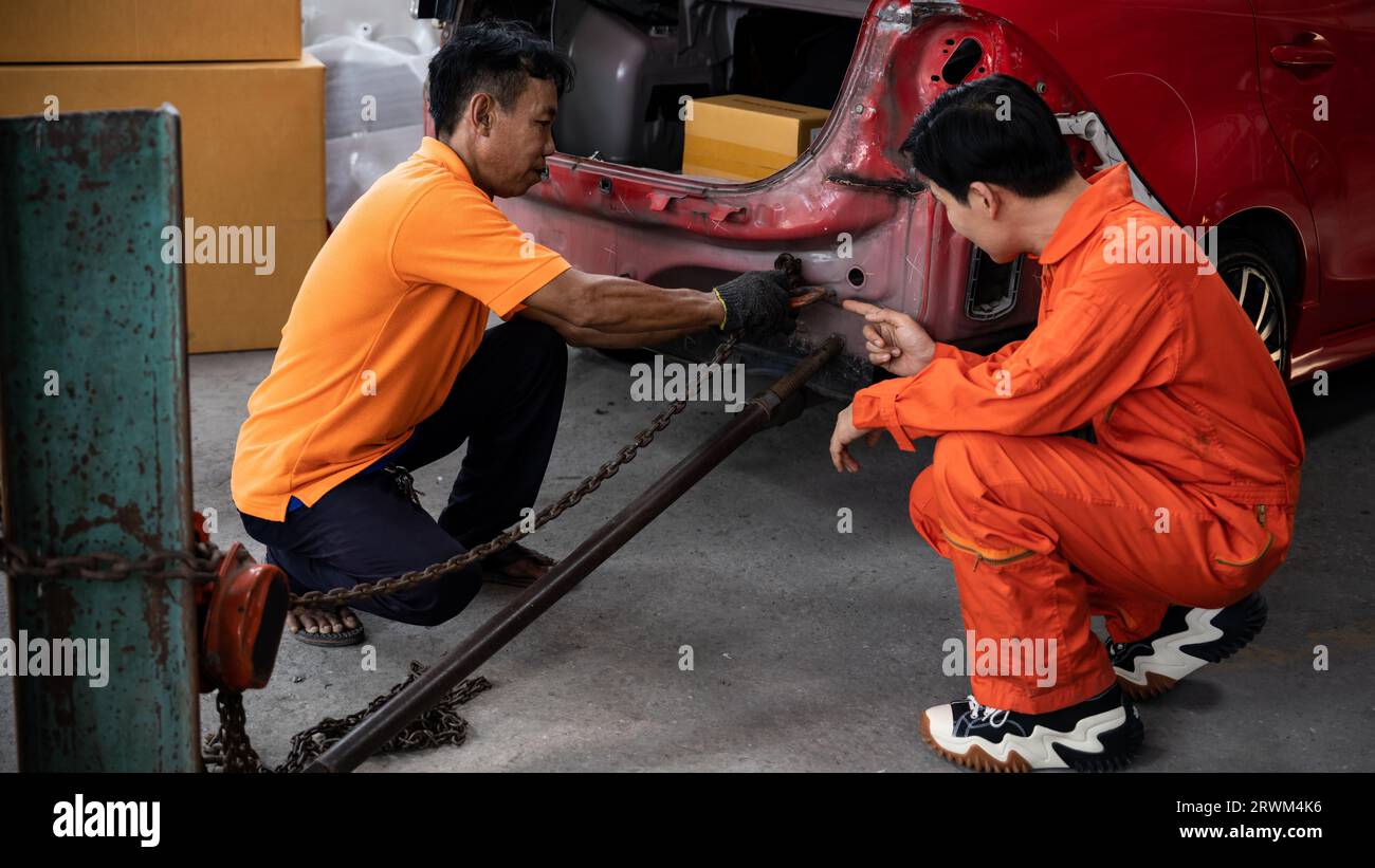 Mechanic testing strength and reliability of chain hoist for car towing