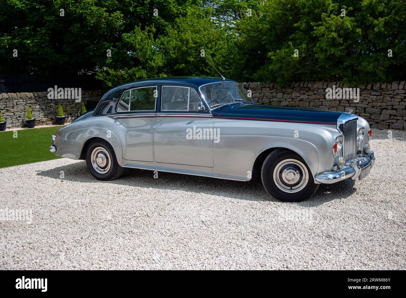 Bentley S3 parked in a rural setting on a gravel drive with a dry stone  and trees behind on a summer day Stock Photo