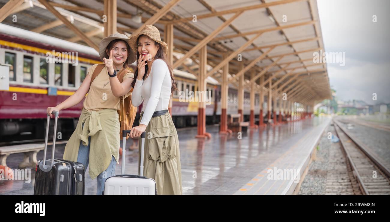 Two women are happy while traveling at the train station. tour concept