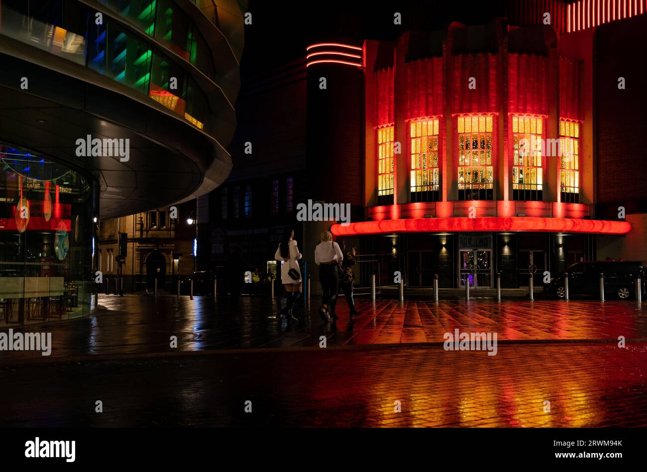 A Night out in Leicester with the Athena club illuminated red and yellow and coloured lights in the Curve Theatre.  Light reflected on wet pavement Stock Photo