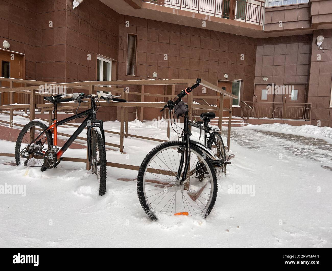 snowy winter. bicycles under snow parked in courtyard of apartment building. Image with selective focus and noise effect Stock Photo