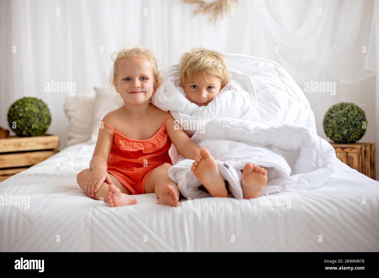 Happy positive children, tickling on the feet, having fun together, boy and girl at home having wonderful day of joy together Stock Photo