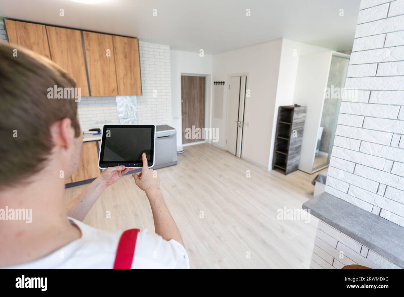 Worker with tablet computer checking alarm system indoors. Stock Photo