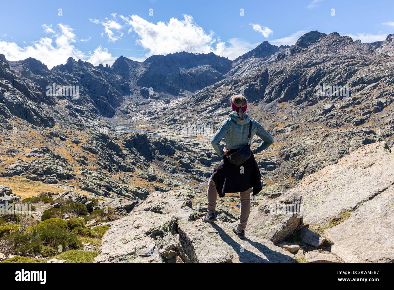 Female tourist hiking to the Laguna Grande de Gredos in Sierra de Gredos, high rocky mountains and lake in the background, autumn view. Stock Photo