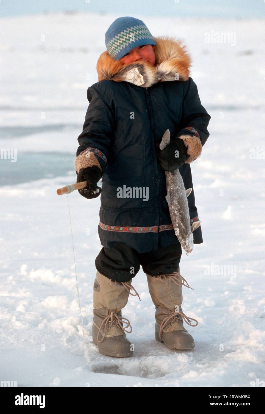 Kanada, Provinz Quebec, Nunavik: Eskimo--Junge angelt durch ein Loch im Eis | Inuit boy fishing thru a hole on a lake in Nunavik, Quebec Province, North-Canada Stock Photo