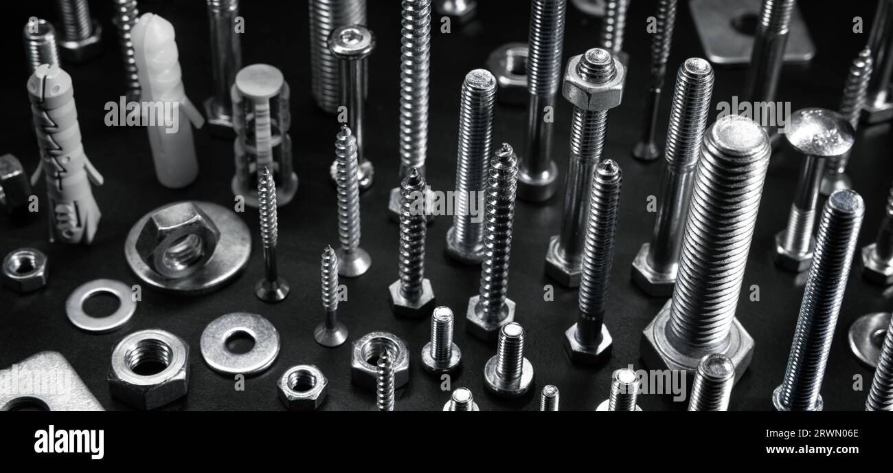 various metal screws, bolts and fasteners on black background Stock Photo