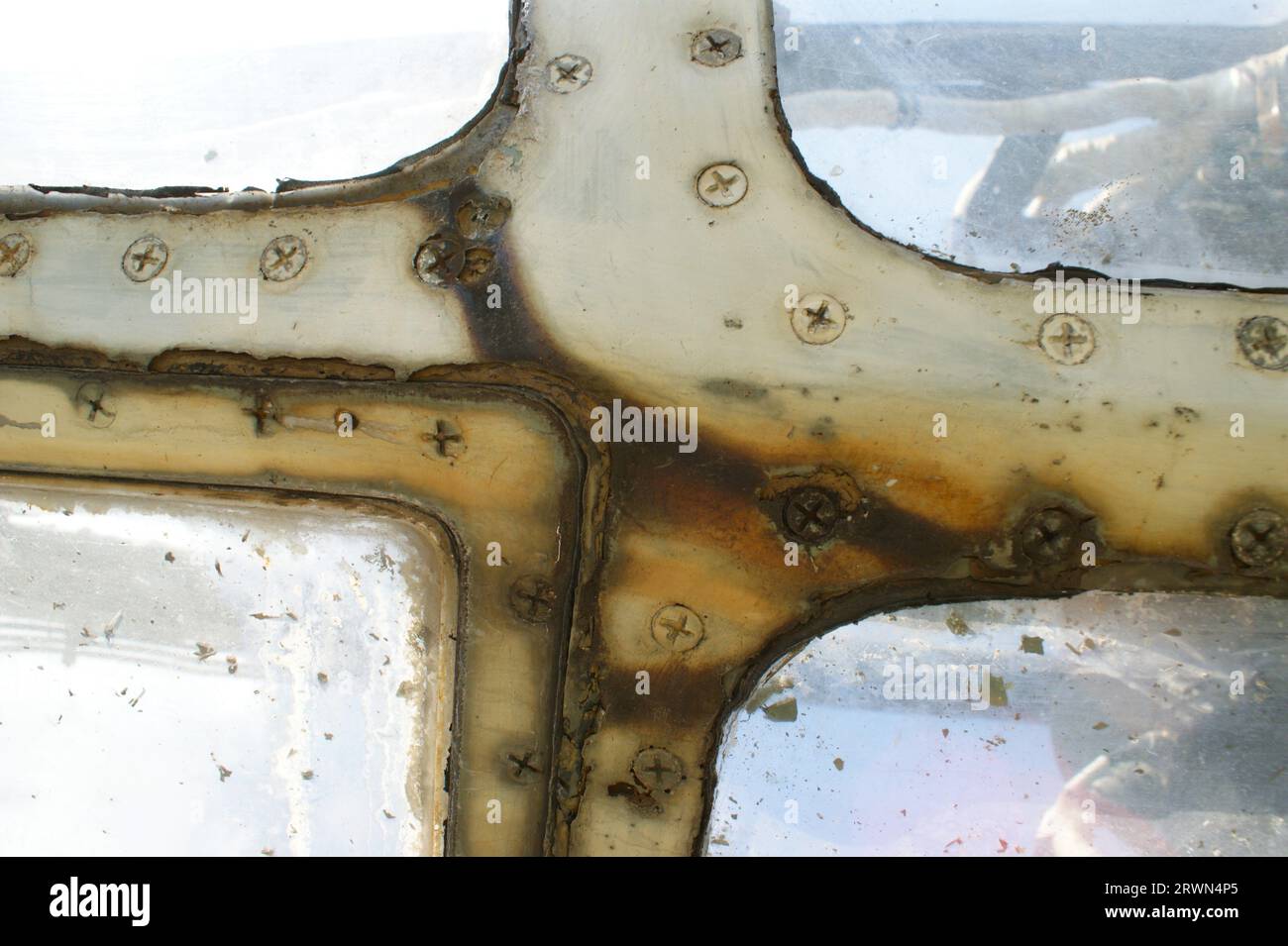 Rusty window frame of an old airplane with screws. Fragment of an airplane. Stock Photo