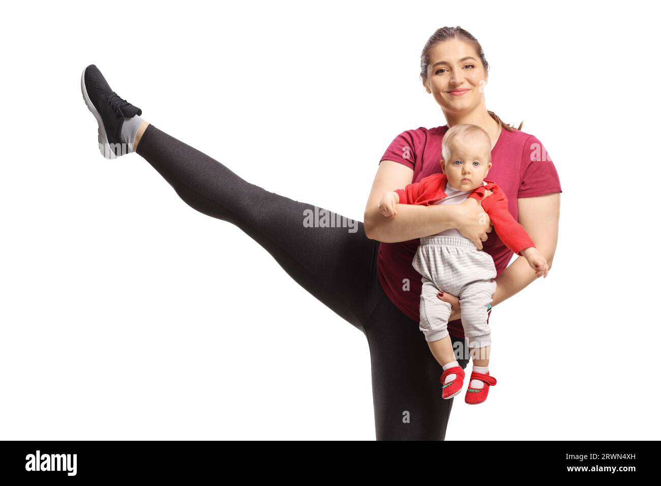 Mother exercising, lifting a leg and holding a baby isolated on white