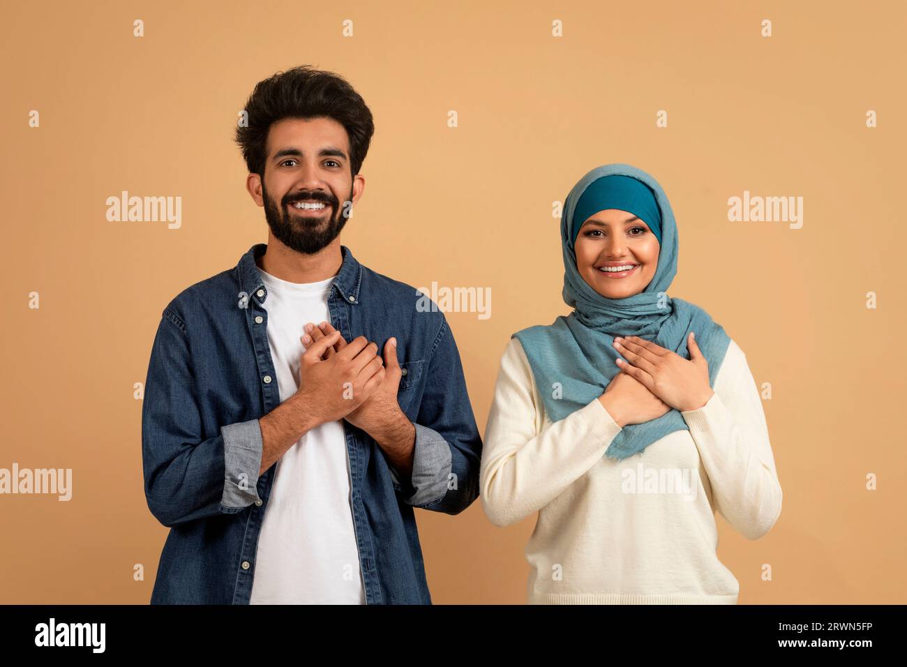 Grateful muslim couple keeping both hands on chest, expressing gratitude and appreciation Stock Photo