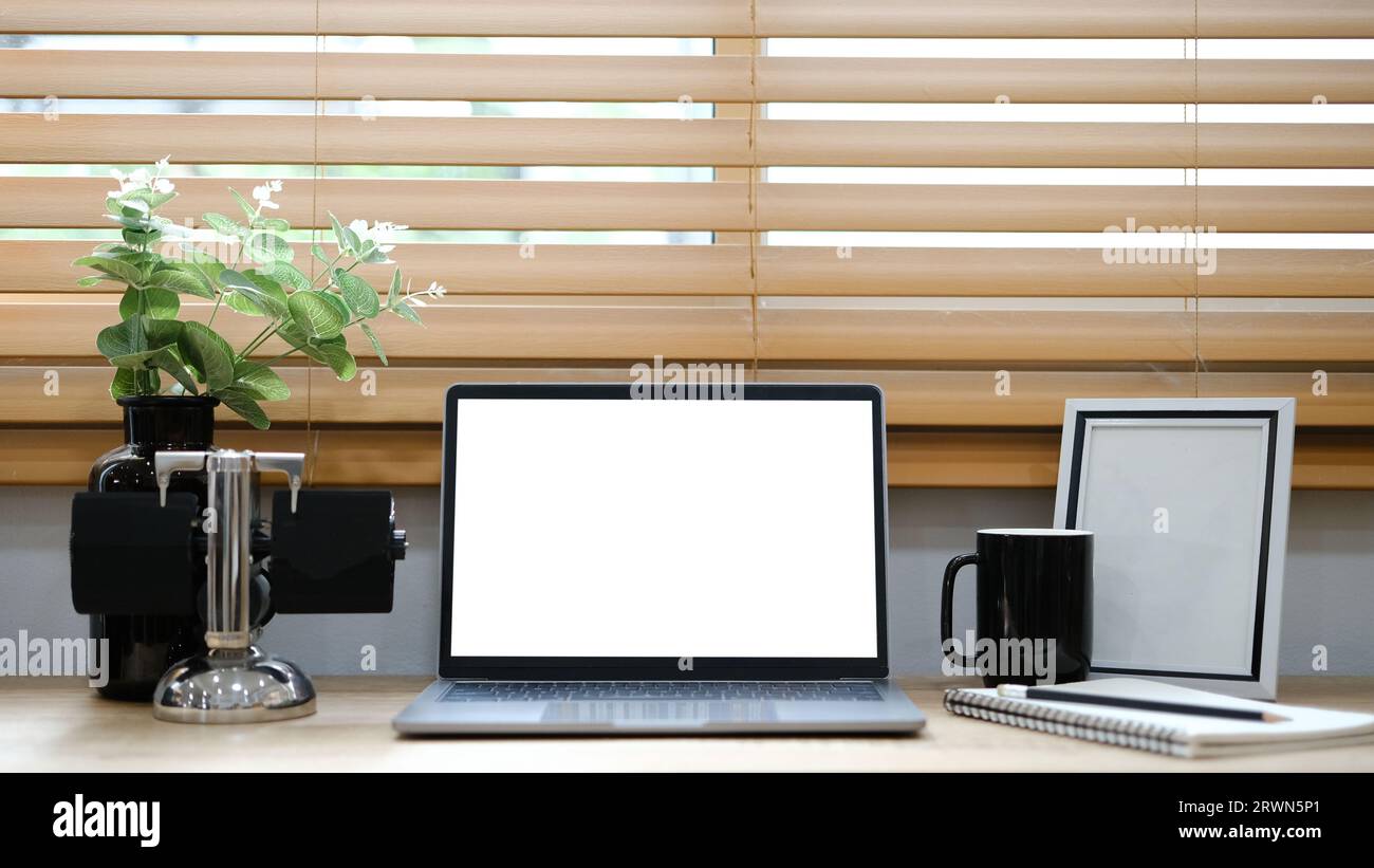 White laptop with blank screen placed on table near window. Stock Photo