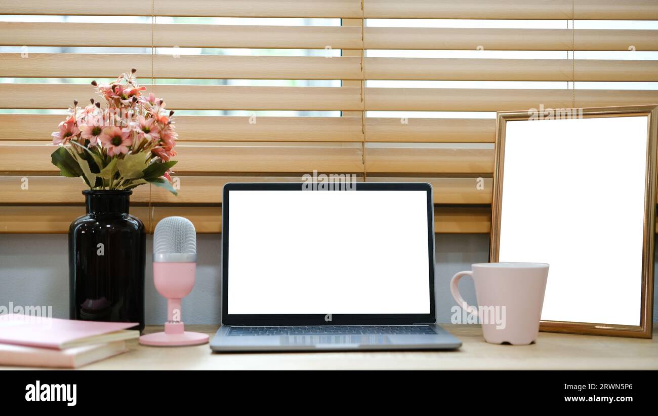 White laptop with blank screen placed on table near window. Stock Photo