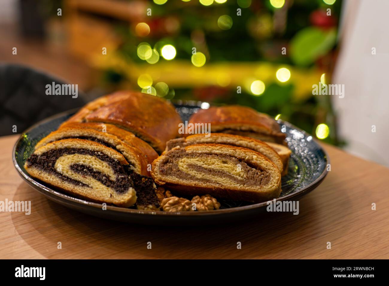 traditional hungarian christmas cookie calles bejgli filled with walnut and poppy seed with christmas tree background . Stock Photo
