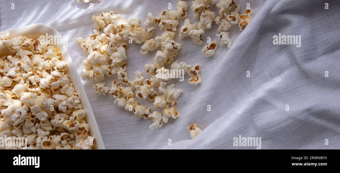Scattered white homemade popcorn in a white bowl,white background , close up.freshly popped popcorn Stock Photo