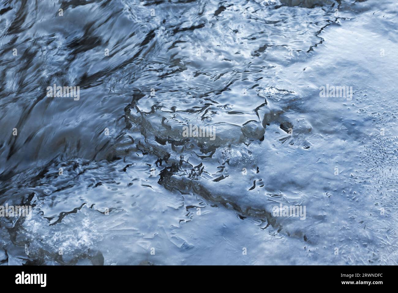 Ice crystal structures are under flowing stream water, close-up natural background photo Stock Photo