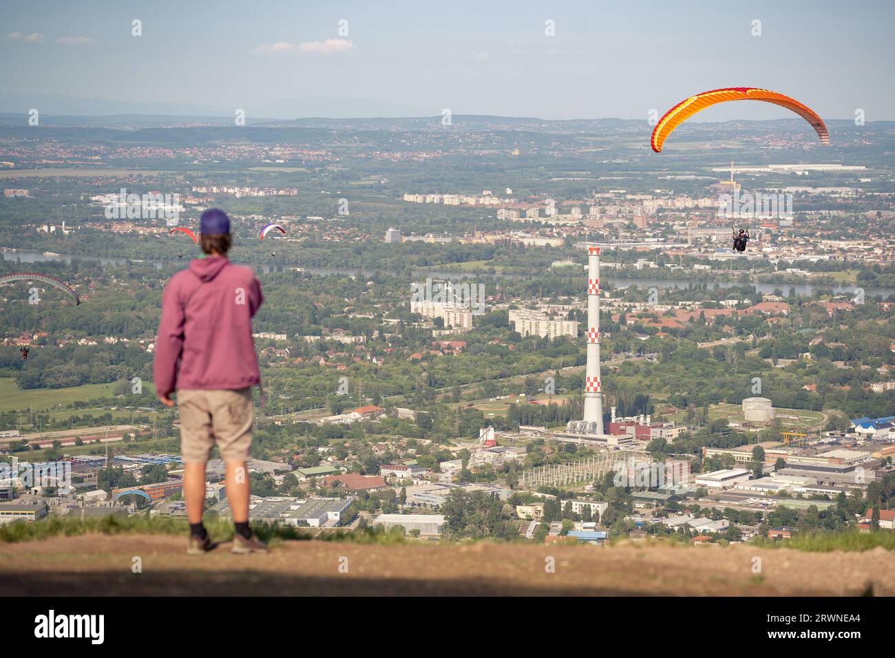 Paragliding over the city. A man assists the paraglider with navigation. Stock Photo