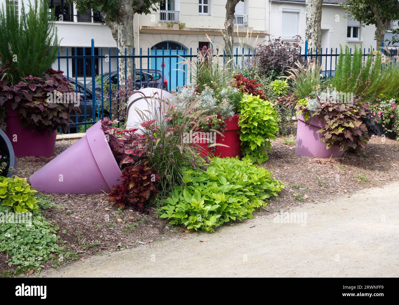 Tipped over coloured planters with foliage plants at the Jardin des Plantes St Nazaire Stock Photo