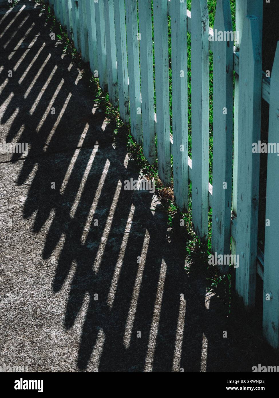 Old-fashioned light blue fence, dropping it's shadows, early in a sunny summer morning Stock Photo