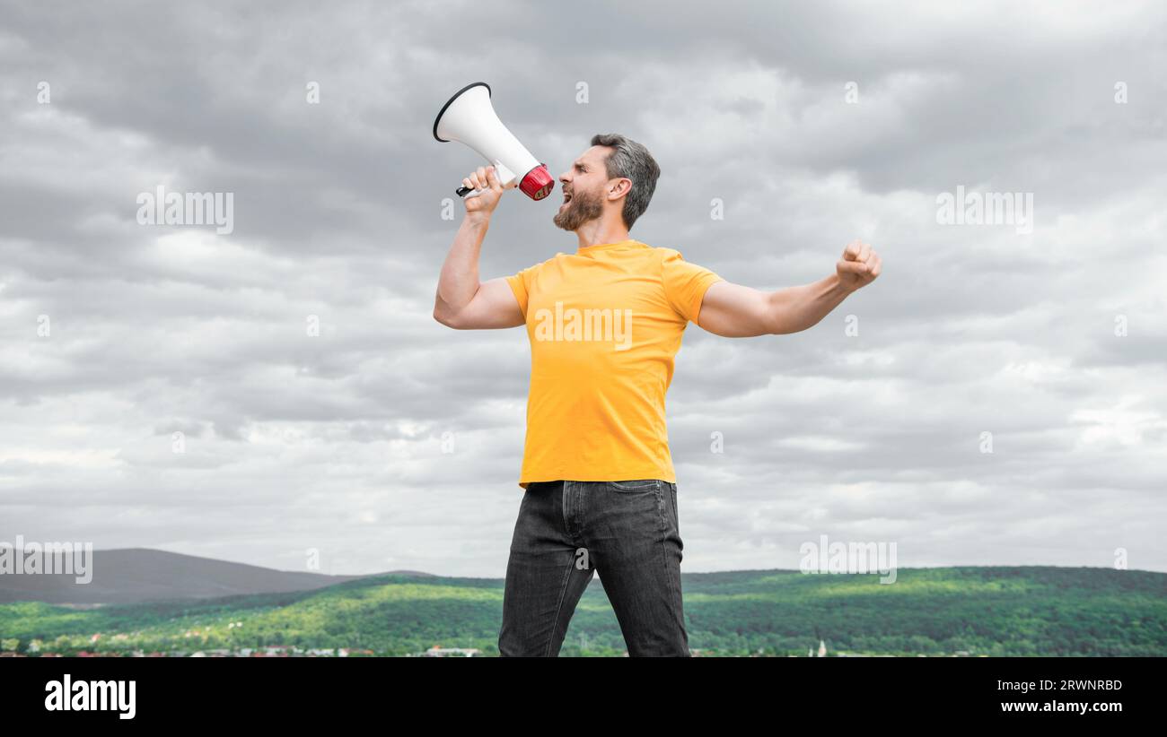 man in yellow shirt announcing in megaphone on sky background Stock ...