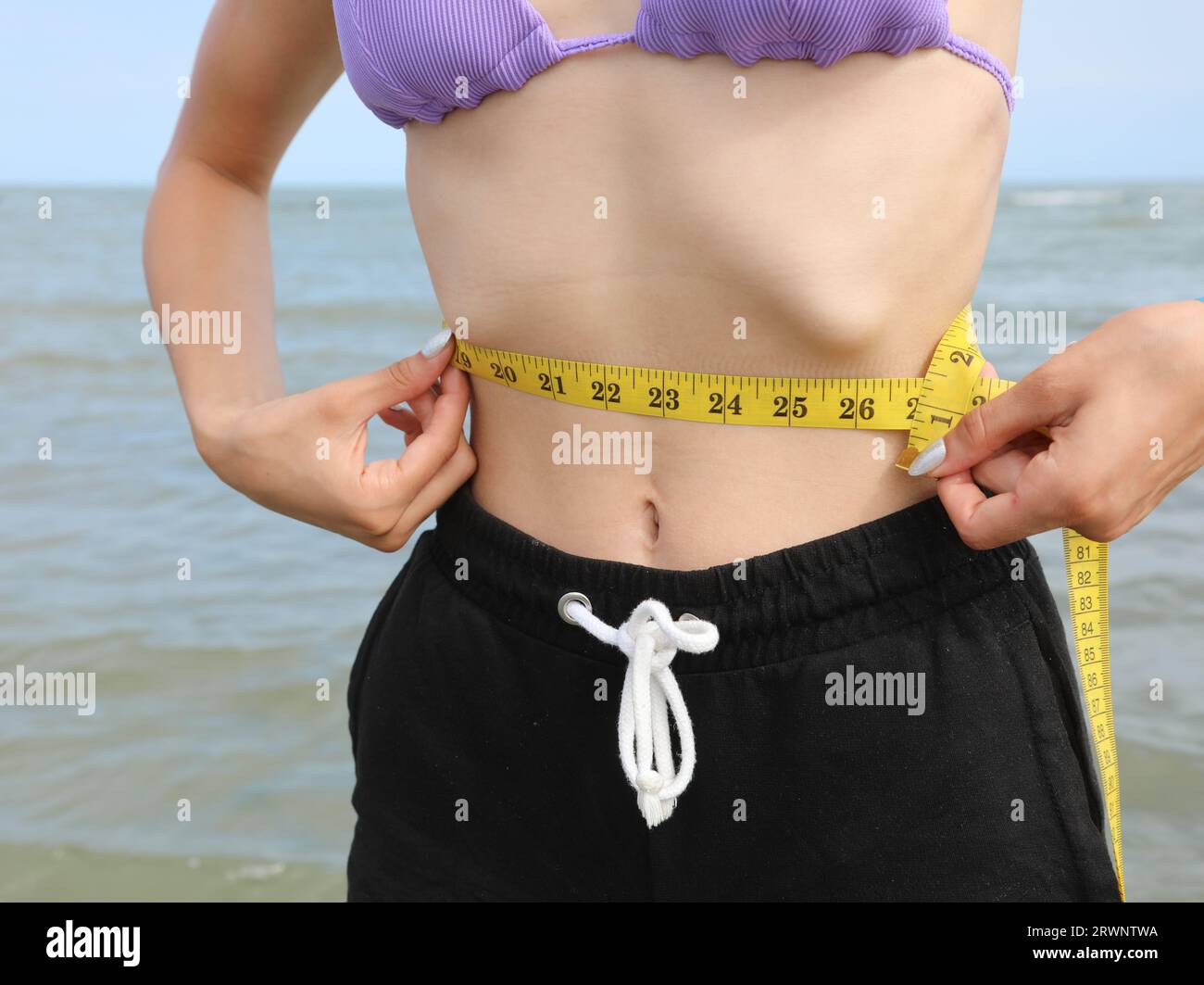 skinny young girl with eating disorder measuring ther waistline Stock Photo