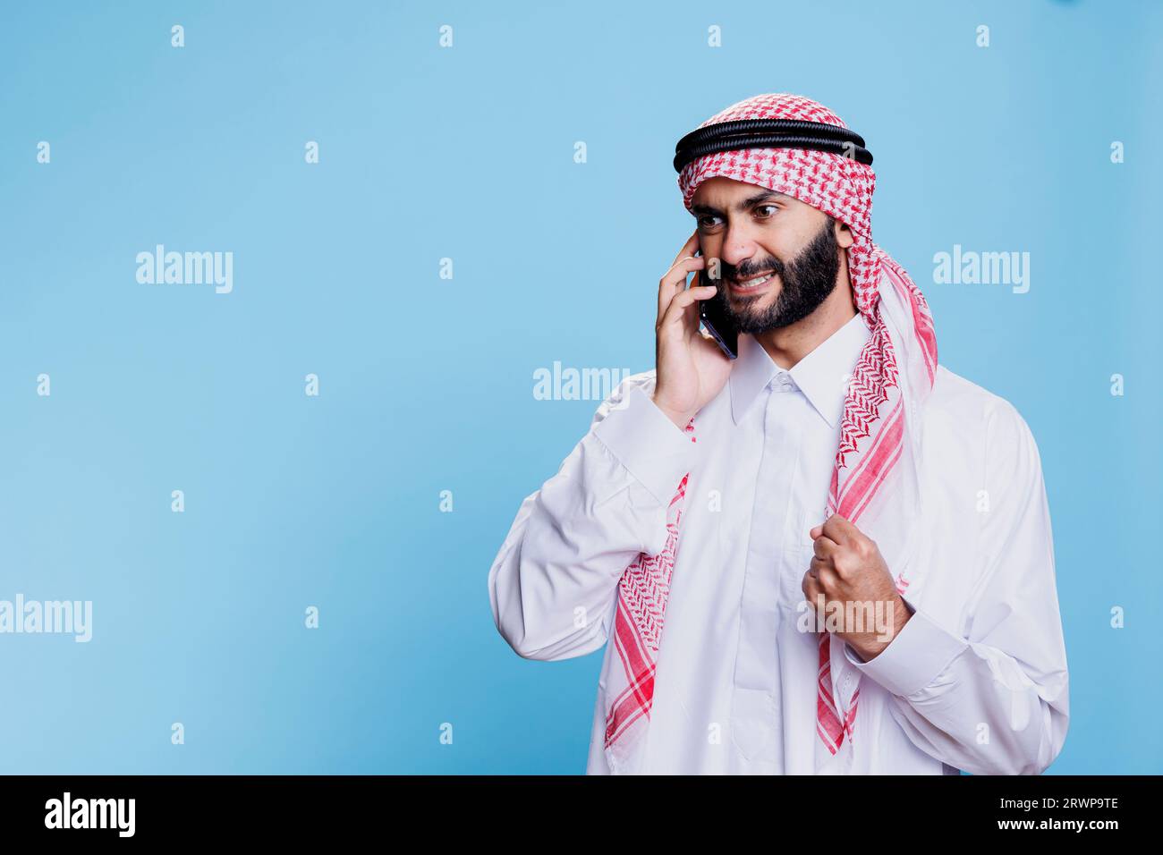 Furious muslim man wearing traditional clothes getting mad while talking on mobile phone