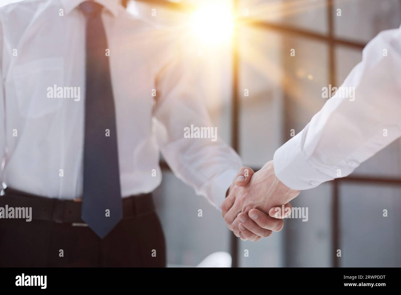 Two businessmen shake hands on the background of empty modern office, signing of a contract concept, close up Stock Photo